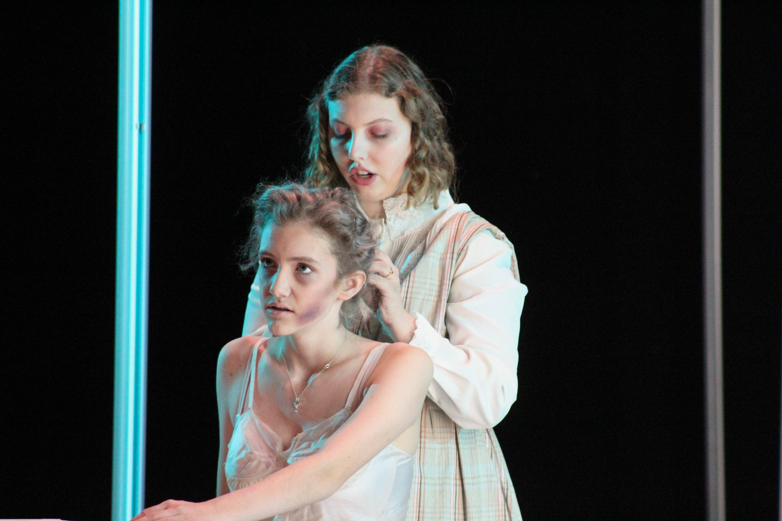 Skye McDonaldVee Ashmun and Lilly Grey onstage in a moving scene as Ashmun’s character, Grace Fryer, is dying from radium poisoning.