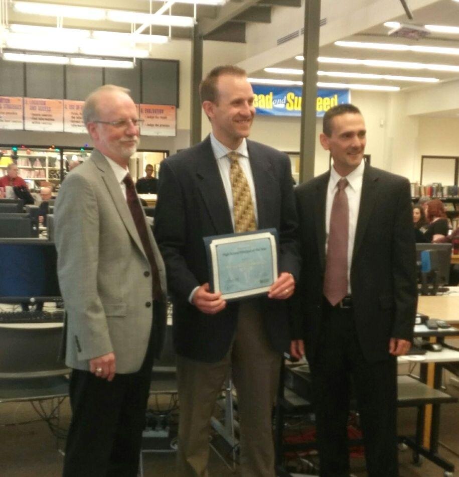 Debbie ArthurPrincipal Keven Wynkoop accepts his award at the staff meeting on April 23, accompanied by Gary Kipp, Executive Director of the Association of Washington School Principals, and Scott Seamen, Director of High Schools and Professional Dev…