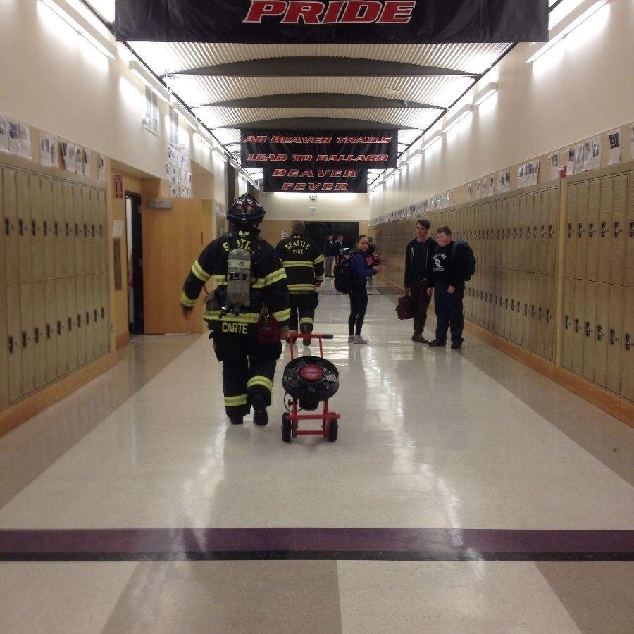 Elliot BaileyTwo Seattle firemen walk through the downstairs hallway to begin a process of smoke removal in the SW boys' bathroom.