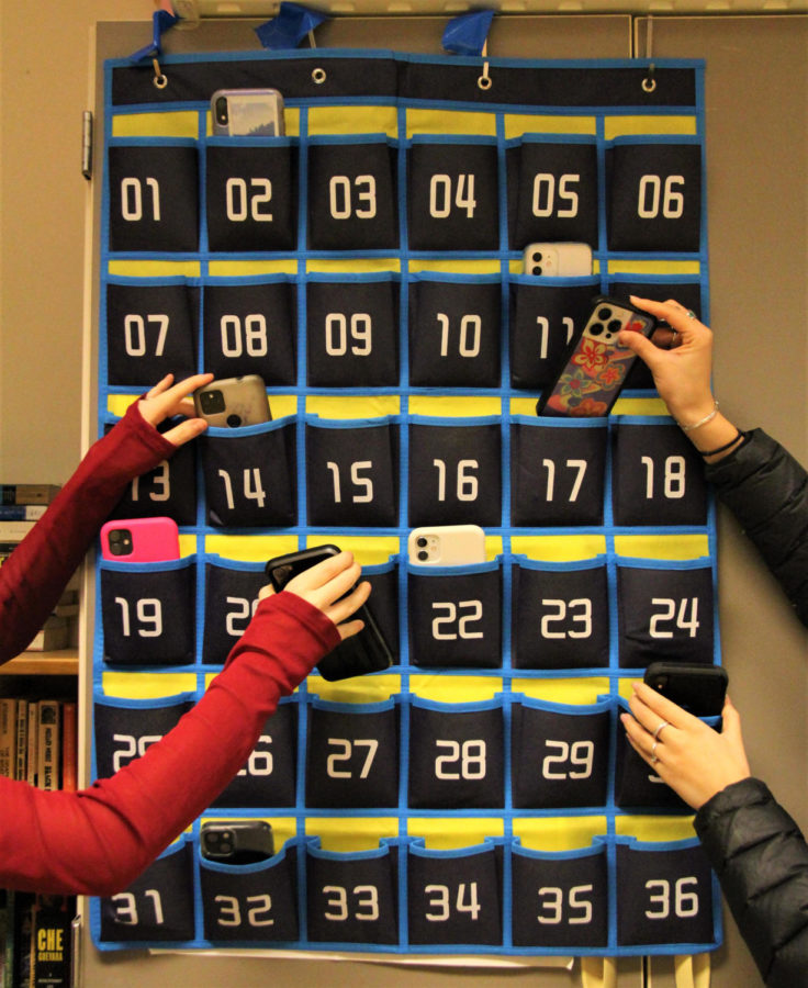 Students+place+phones+into+numbered+hanging+pockets%0Aon+their+classroom+wall.