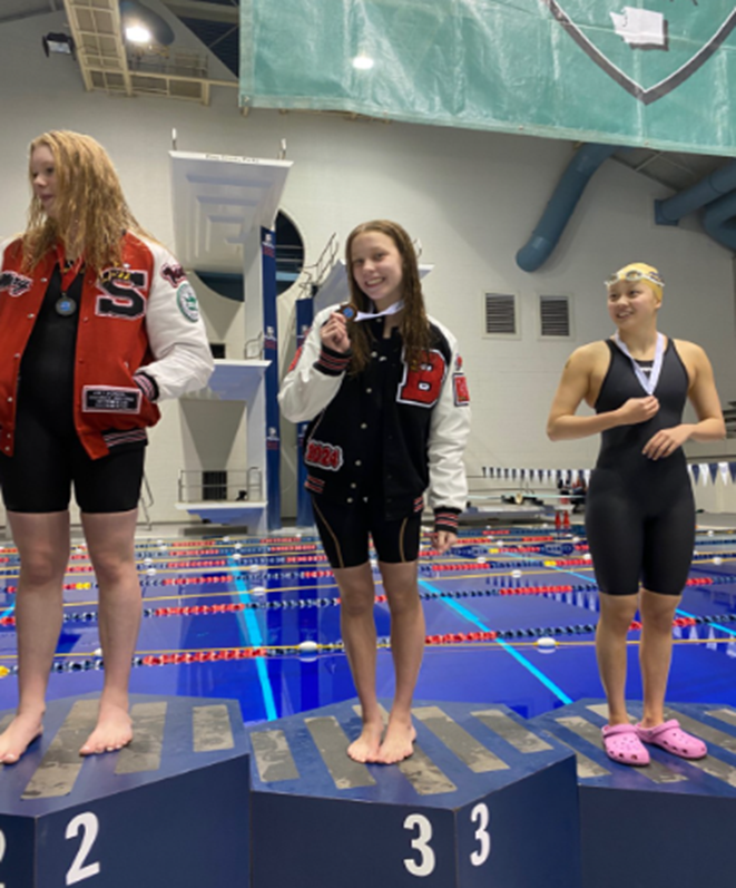 Junior Claudia Yovanovich reflects on her hard work as she raises her medal at the state championship this fall for finishing third in both events, the 100-yard backstroke and the 50-yard freestyle.