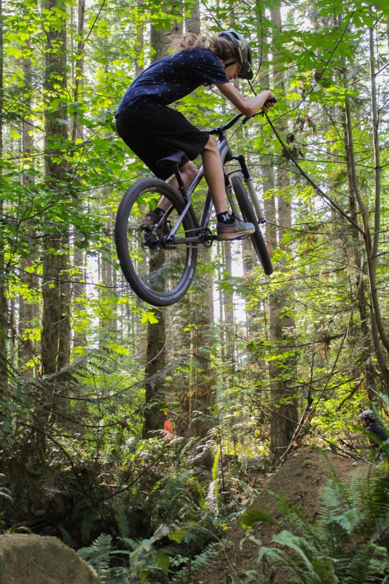 Freshman Lachlan Collis jumping on mountain biking trails.